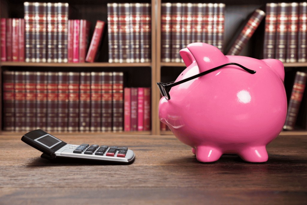 電卓と向き合うメガネをかけたピンクの貯金箱