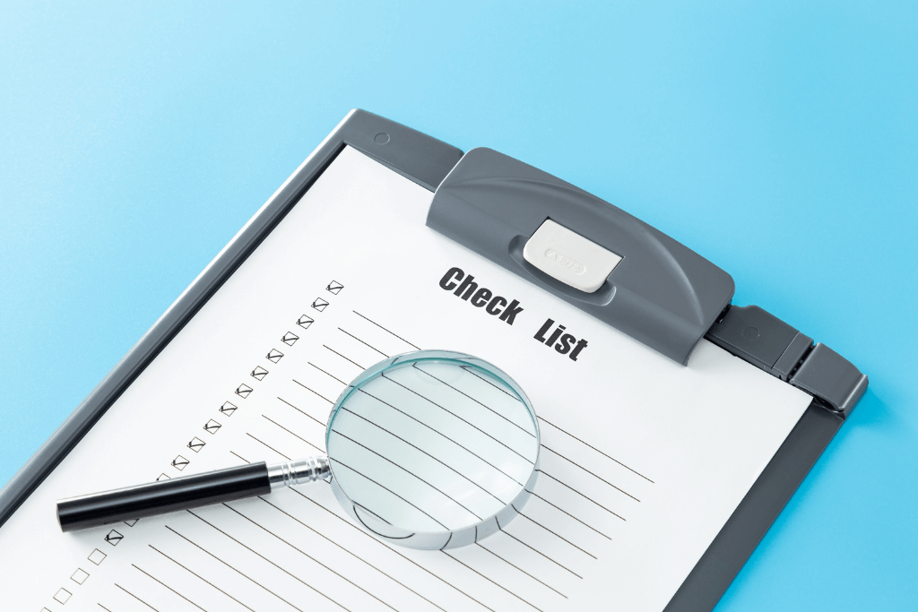 虫眼鏡とボールペンが置かれたチェックリストの書類