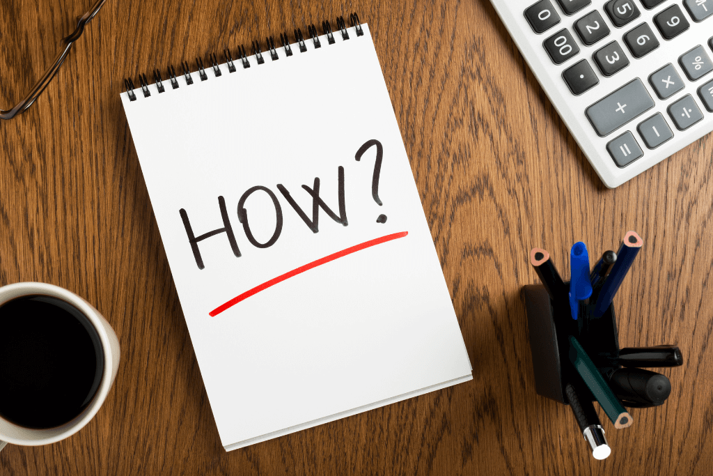 テーブルの上に置かれた「HOW？」と書かれたノート