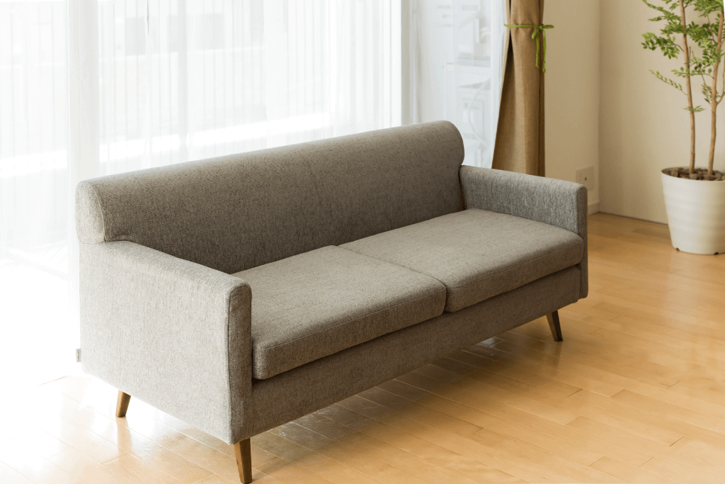 明るい日差しが差し込む部屋に置かれたグレーの2人掛けソファ