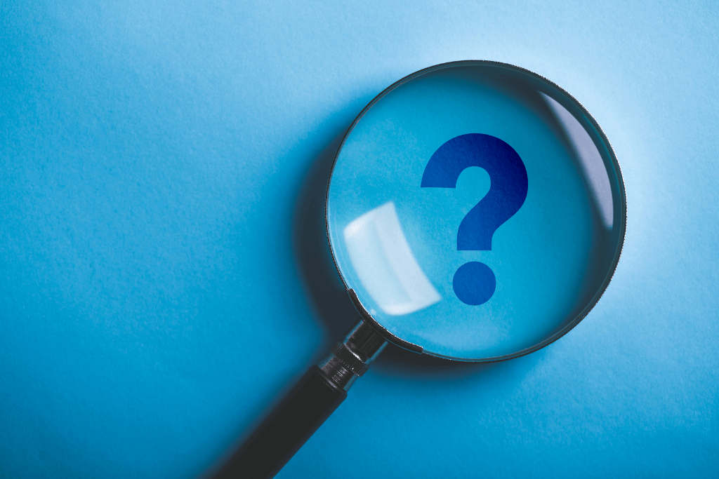 虫眼鏡越しに見える青地に描かれた疑問符