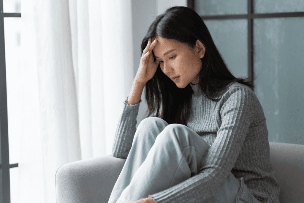 不安そうな表情でソファに座る女性