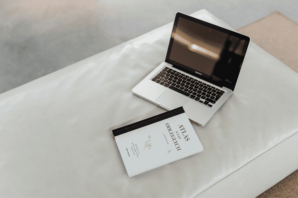 ノートパソコンと本が置かれた白いソファの座面