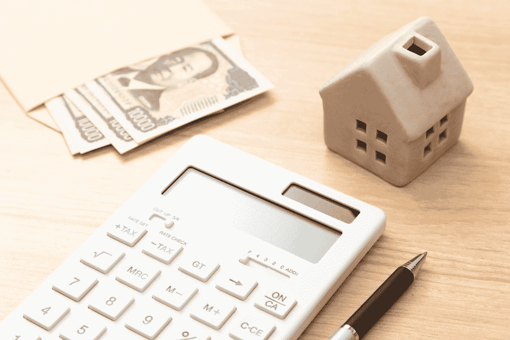 電卓と家の模型、現金を並べた節約イメージ