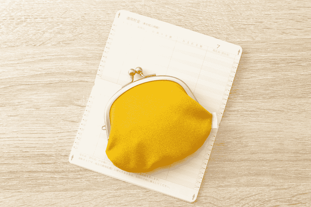 スケジュール帳の上に置かれた黄色いがま口財布