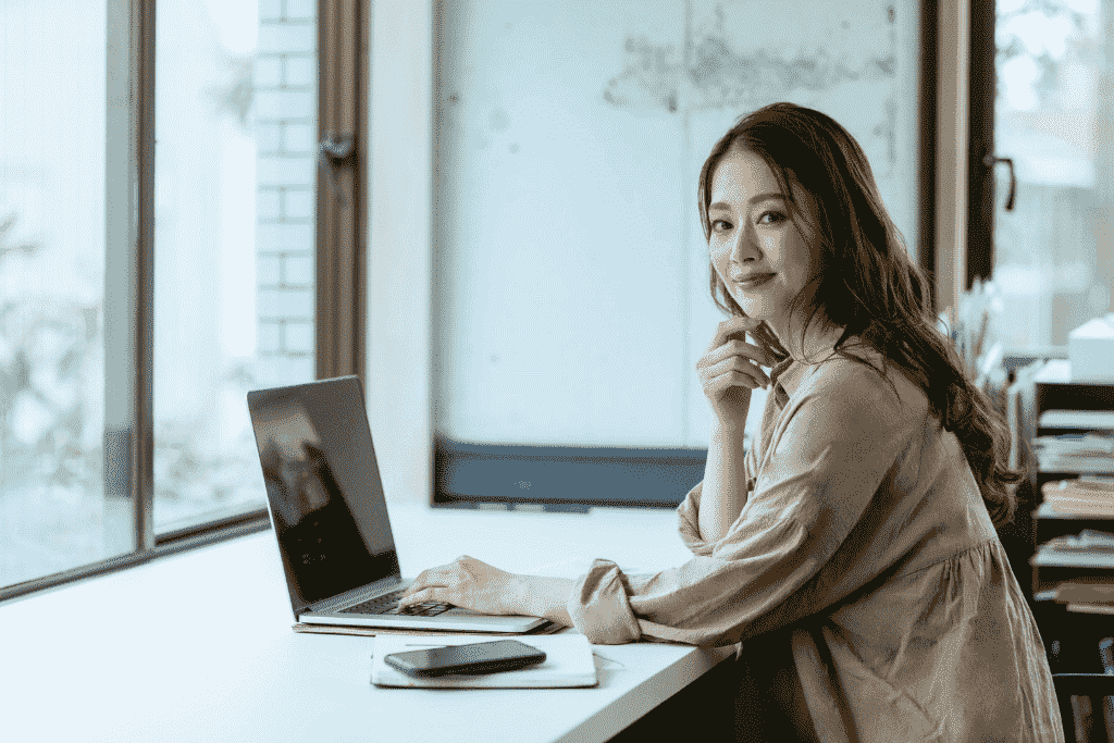 ノートパソコンの前で微笑む女性
