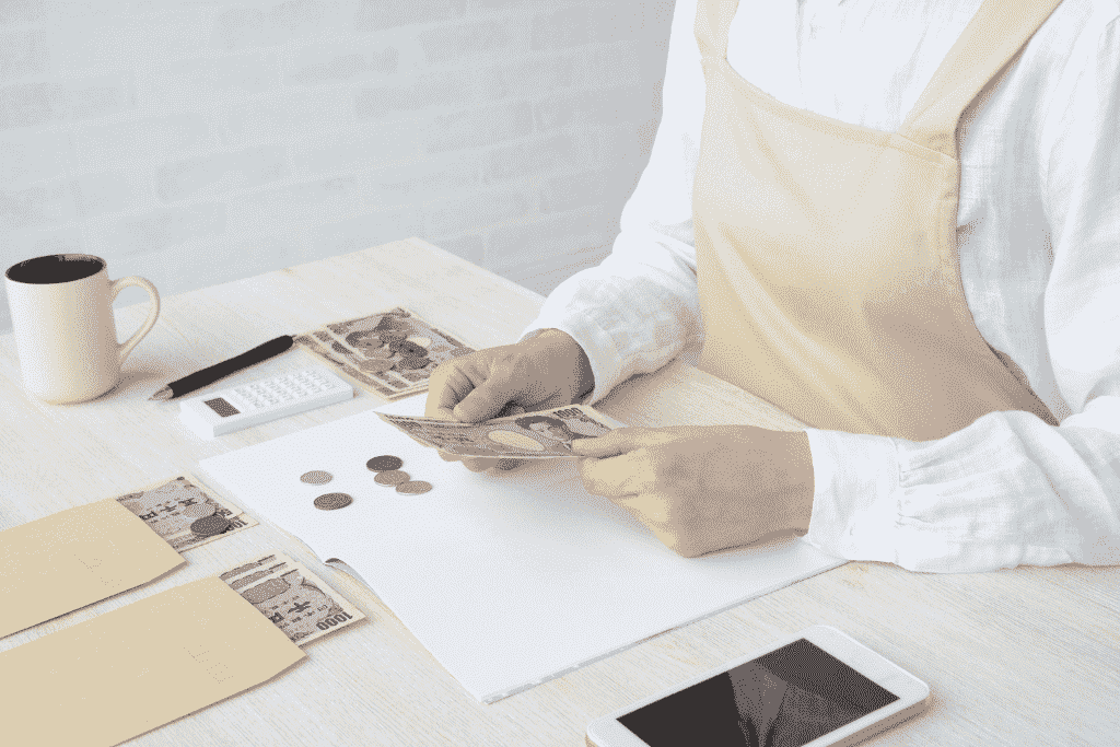 家計簿をつけながらお金を数える女性