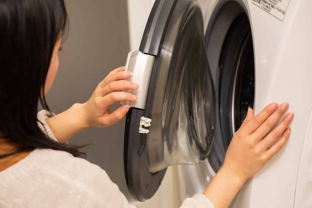 洗濯機の蓋をあける女性